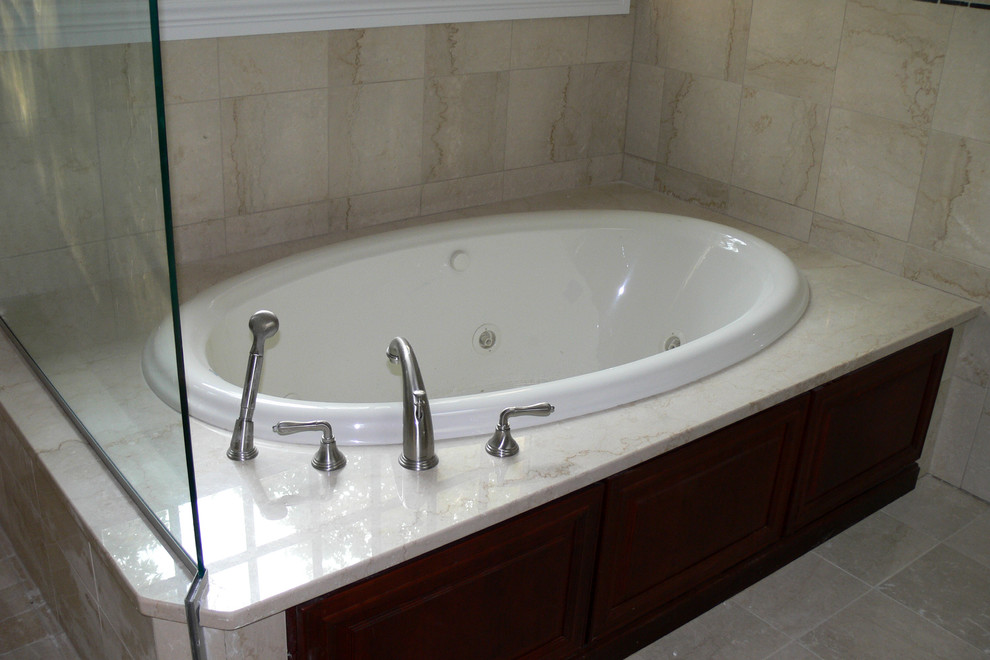 Example of a classic master stone tile marble floor drop-in bathtub design in New York
