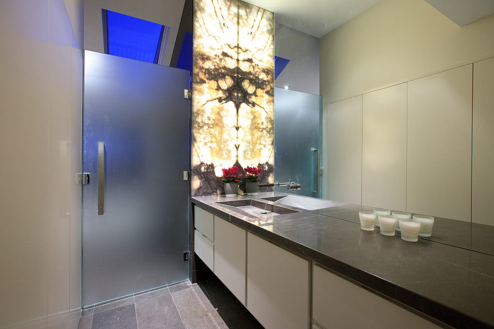 Foto på ett mellanstort funkis badrum, med släta luckor, vita skåp, en dusch i en alkov, vita väggar, kalkstensgolv och ett avlångt handfat