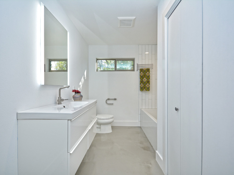 Example of a small minimalist 3/4 white tile and subway tile concrete floor tub/shower combo design in Austin with flat-panel cabinets, white cabinets, a two-piece toilet, white walls, an integrated sink and solid surface countertops