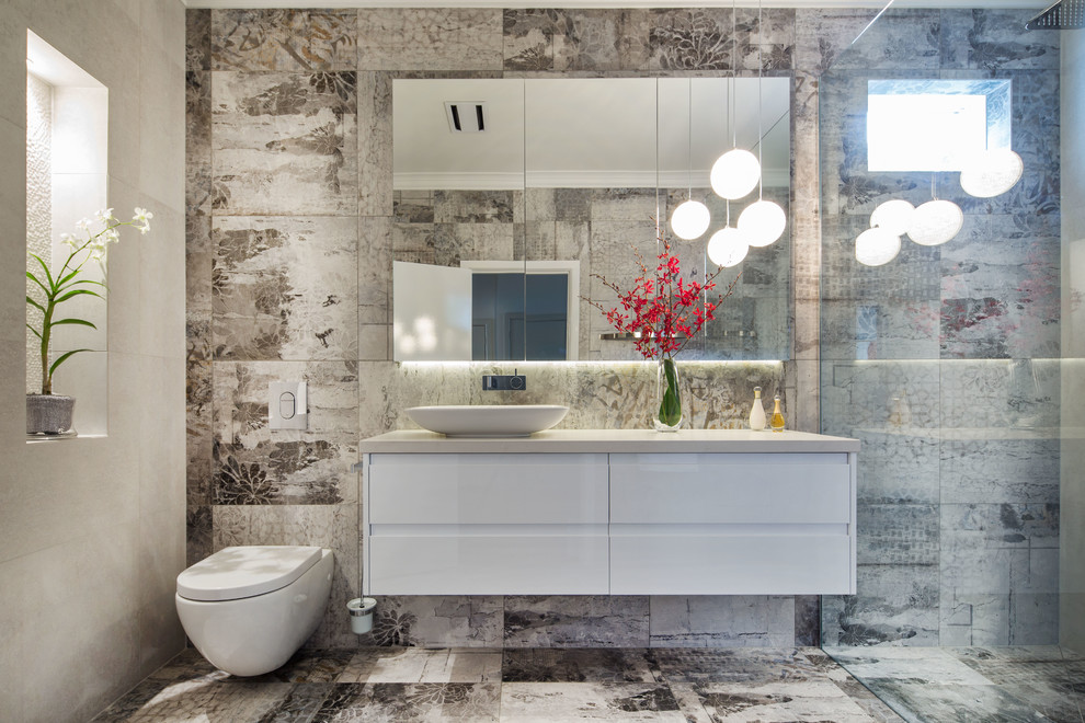 Modern inredning av ett mellanstort badrum med dusch, med vita skåp, en öppen dusch, en vägghängd toalettstol, grå kakel, porslinskakel, grå väggar, klinkergolv i porslin, ett fristående handfat och bänkskiva i kvarts