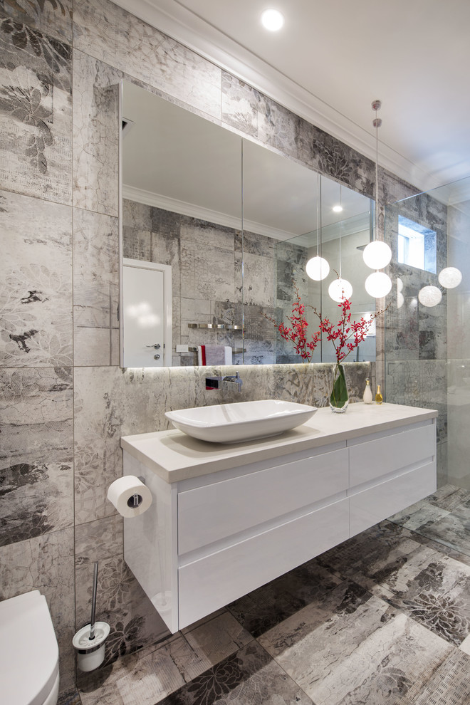 Example of a mid-sized minimalist 3/4 gray tile and porcelain tile porcelain tile doorless shower design in Melbourne with white cabinets, a wall-mount toilet, gray walls, a vessel sink and quartz countertops