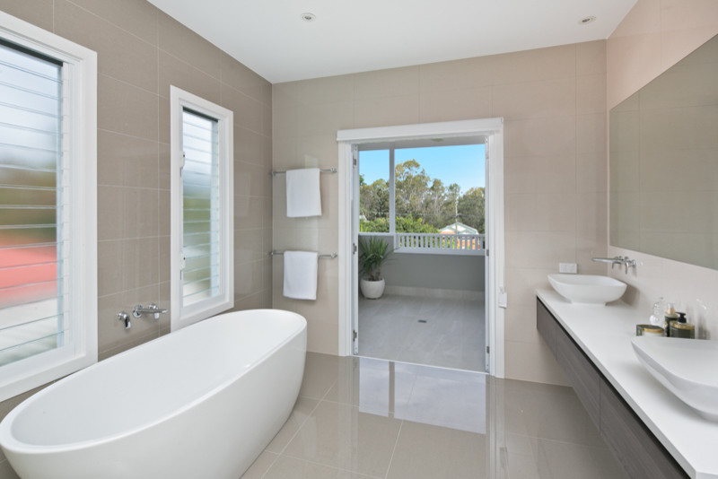 На фото: ванная комната в современном стиле с серыми фасадами, отдельно стоящей ванной, настольной раковиной и мраморной столешницей с