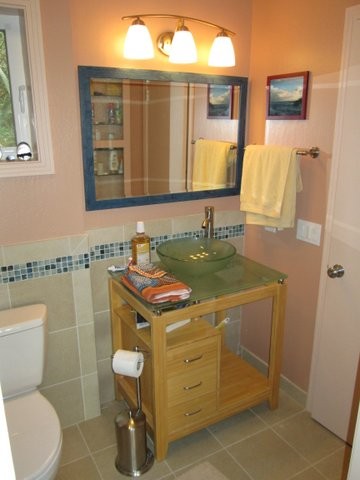 На фото: ванная комната с настольной раковиной, фасадами островного типа, светлыми деревянными фасадами, стеклянной столешницей, угловым душем, раздельным унитазом, бежевой плиткой и плиткой кабанчик