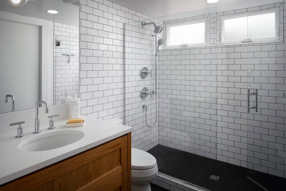 Idéer för att renovera ett mellanstort funkis vit vitt badrum, med luckor med infälld panel, skåp i mellenmörkt trä, en toalettstol med hel cisternkåpa, vit kakel, keramikplattor, vita väggar, klinkergolv i keramik, ett undermonterad handfat, bänkskiva i kvarts, svart golv och dusch med gångjärnsdörr