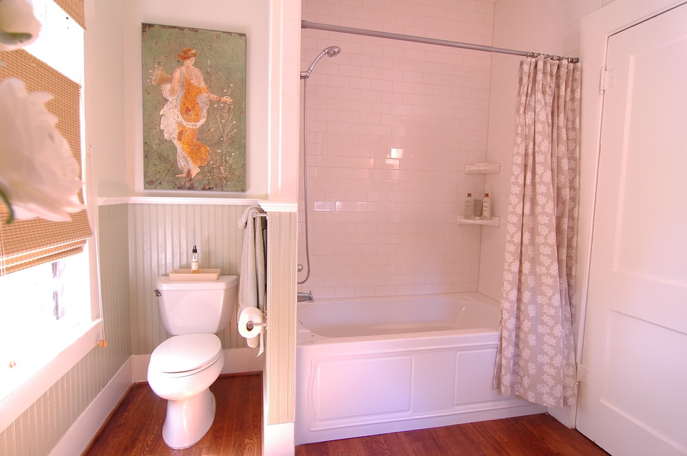 Photo of a medium sized traditional bathroom in Dallas with an alcove bath, a shower/bath combination, white tiles, metro tiles, a two-piece toilet, white walls, medium hardwood flooring and a shower curtain.
