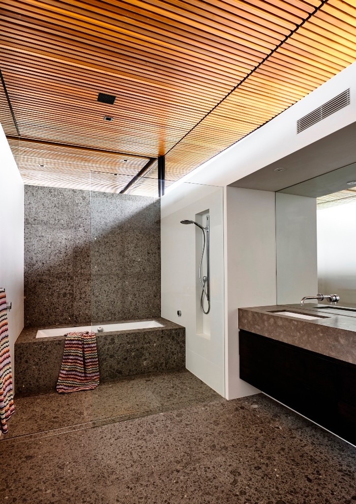 Immagine di una stanza da bagno per bambini contemporanea con ante nere, vasca sottopiano, doccia aperta, pareti bianche, pavimento in pietra calcarea e lavabo sottopiano