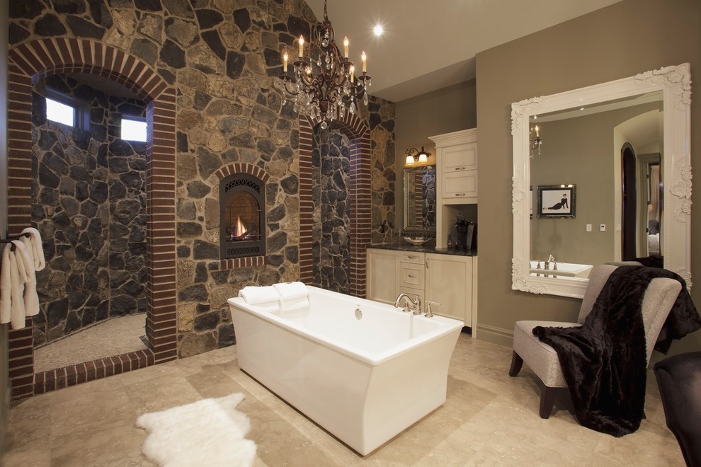 Klassisches Badezimmer mit Aufsatzwaschbecken, freistehender Badewanne, beigen Fliesen und Steinwänden in Calgary