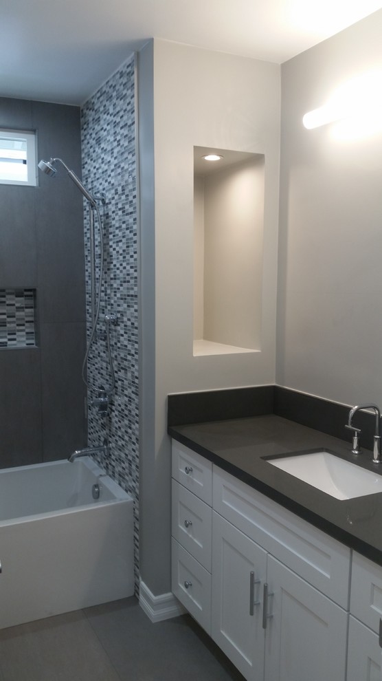 Cette image montre une petite salle de bain traditionnelle avec un placard sans porte, des portes de placard blanches, une baignoire en alcôve, un carrelage gris, un mur gris, un lavabo encastré, une cabine de douche à porte battante, des carreaux en allumettes, sol en béton ciré, un plan de toilette en béton, un sol gris et un plan de toilette gris.