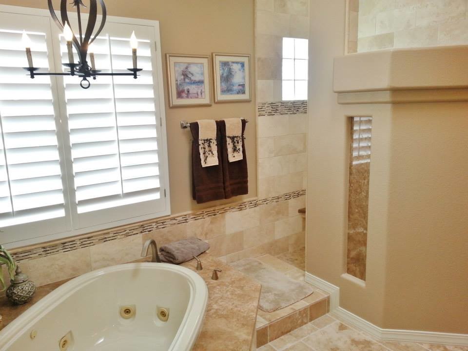 Exempel på ett mycket stort amerikanskt en-suite badrum, med ett nedsänkt handfat, luckor med upphöjd panel, skåp i mörkt trä, granitbänkskiva, ett platsbyggt badkar, en hörndusch, beige kakel, stenkakel, beige väggar och travertin golv