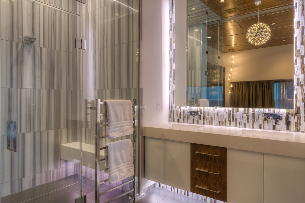 Modern inredning av ett mycket stort en-suite badrum, med ett integrerad handfat, släta luckor, vita skåp, bänkskiva i kvartsit, en kantlös dusch, flerfärgad kakel, mosaik, vita väggar och klinkergolv i keramik