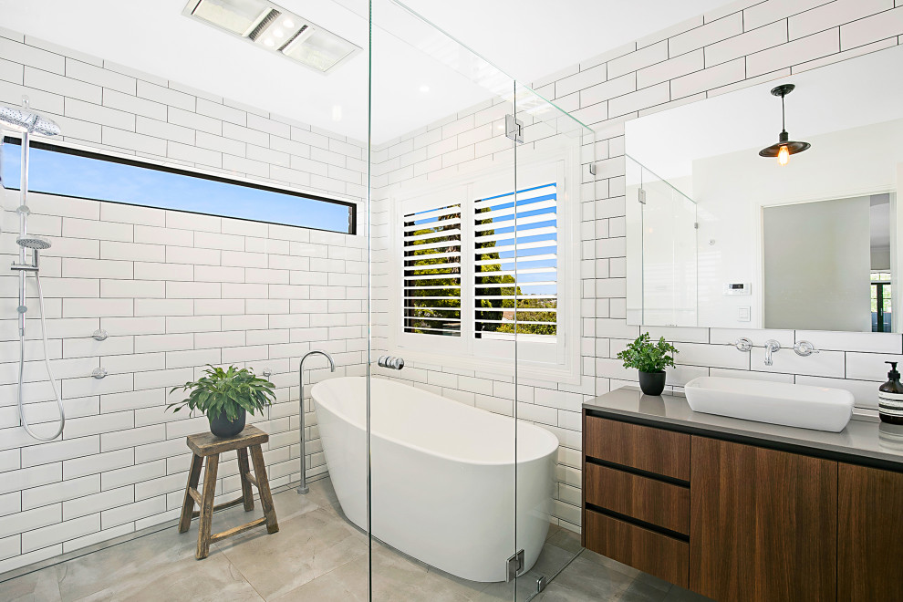 Inredning av ett modernt mellanstort grå grått en-suite badrum, med släta luckor, skåp i mellenmörkt trä, ett fristående badkar, våtrum, vit kakel, tunnelbanekakel, ett fristående handfat, grått golv och med dusch som är öppen