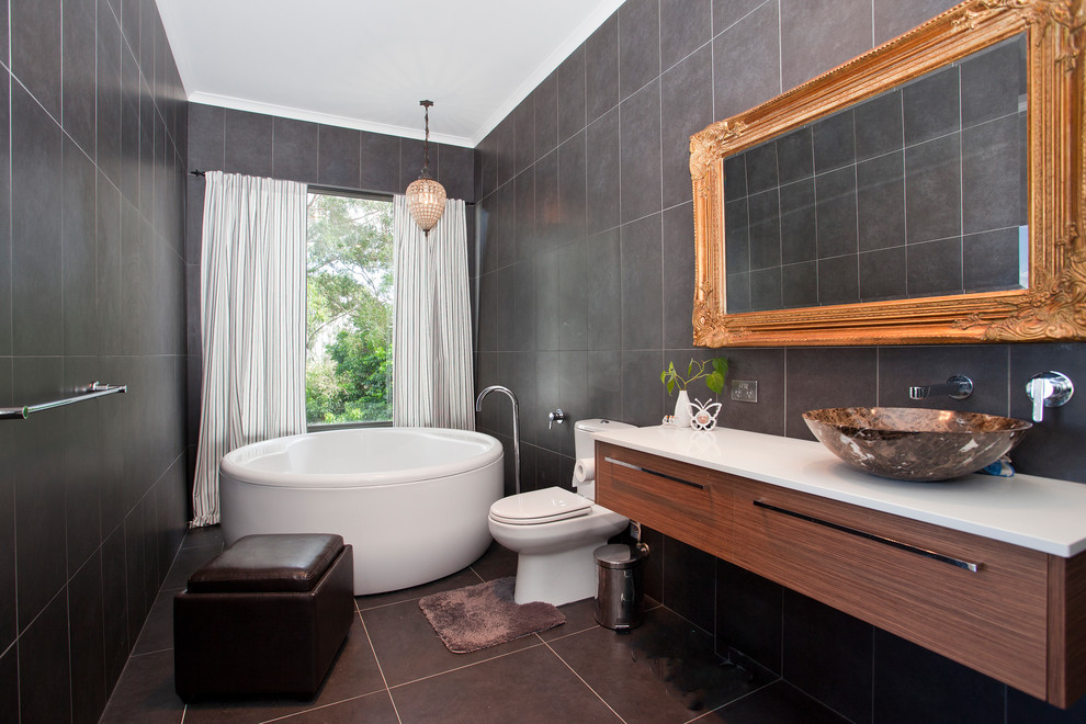 Cette image montre une salle de bain principale design en bois foncé avec un placard à porte plane, un carrelage gris, une vasque et un sol gris.
