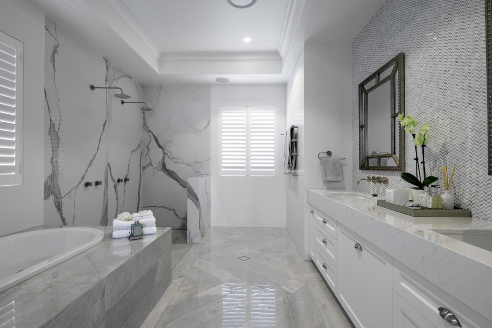 Bild på ett mellanstort funkis vit vitt badrum, med möbel-liknande, vita skåp, ett undermonterat badkar, en dusch/badkar-kombination, en vägghängd toalettstol, vit kakel, keramikplattor, vita väggar, klinkergolv i keramik, ett undermonterad handfat, bänkskiva i kvarts, grått golv och med dusch som är öppen