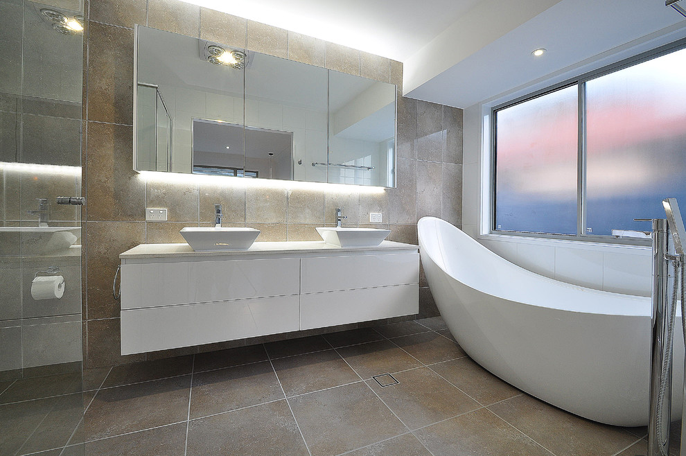 Свежая идея для дизайна: ванная комната в стиле модернизм с настольной раковиной, белыми фасадами, отдельно стоящей ванной и полом из керамогранита - отличное фото интерьера