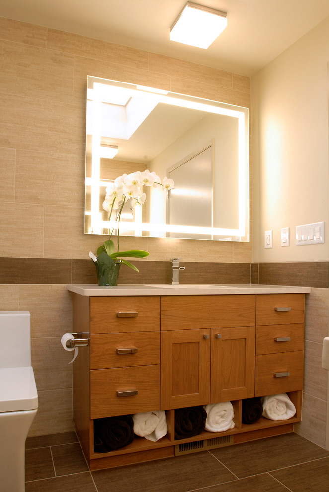 This is an example of a small contemporary shower room bathroom in Seattle with a submerged sink, flat-panel cabinets, light wood cabinets, engineered stone worktops, a built-in bath, an alcove shower, a one-piece toilet, beige tiles, porcelain tiles, beige walls and porcelain flooring.