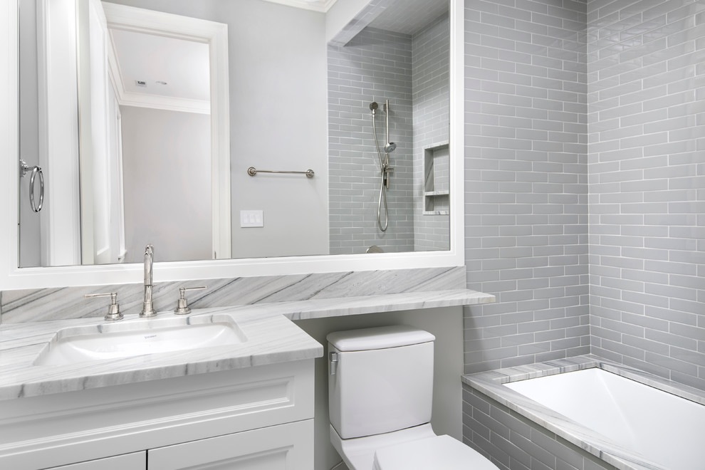 Inredning av ett klassiskt stort en-suite badrum, med ett undermonterad handfat, luckor med infälld panel, vita skåp, marmorbänkskiva, ett undermonterat badkar, en dusch i en alkov, grå kakel, stenhäll, grå väggar och marmorgolv