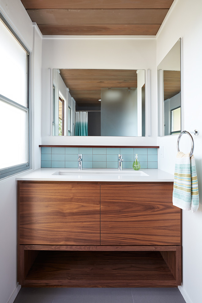 Идея дизайна: ванная комната в стиле ретро с плоскими фасадами, фасадами цвета дерева среднего тона, синей плиткой, белыми стенами, врезной раковиной, серым полом и белой столешницей