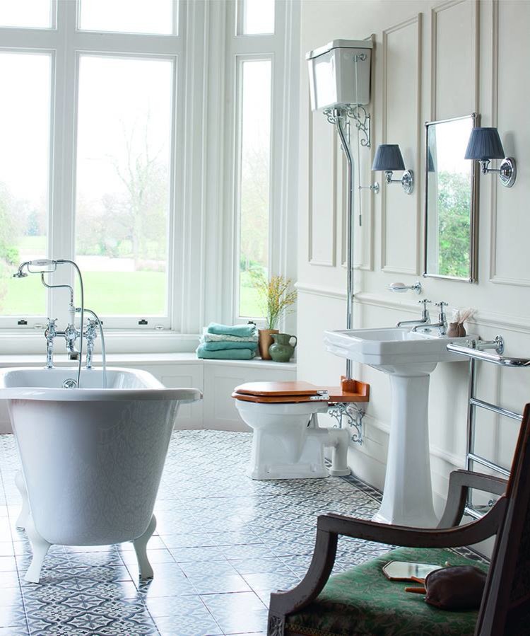 This is an example of a medium sized traditional family bathroom in Cambridgeshire with shaker cabinets, medium wood cabinets, a claw-foot bath, a built-in shower, a one-piece toilet, white tiles, ceramic tiles, white walls, porcelain flooring, a pedestal sink and marble worktops.