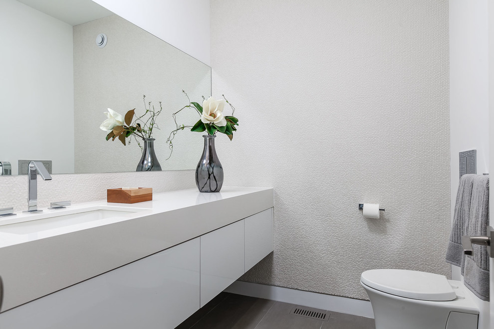 Idee per una stanza da bagno minimalista con ante bianche, WC sospeso, pareti bianche, lavabo sottopiano, top in quarzo composito, ante lisce, piastrelle bianche, piastrelle in ceramica, pavimento in gres porcellanato e pavimento grigio
