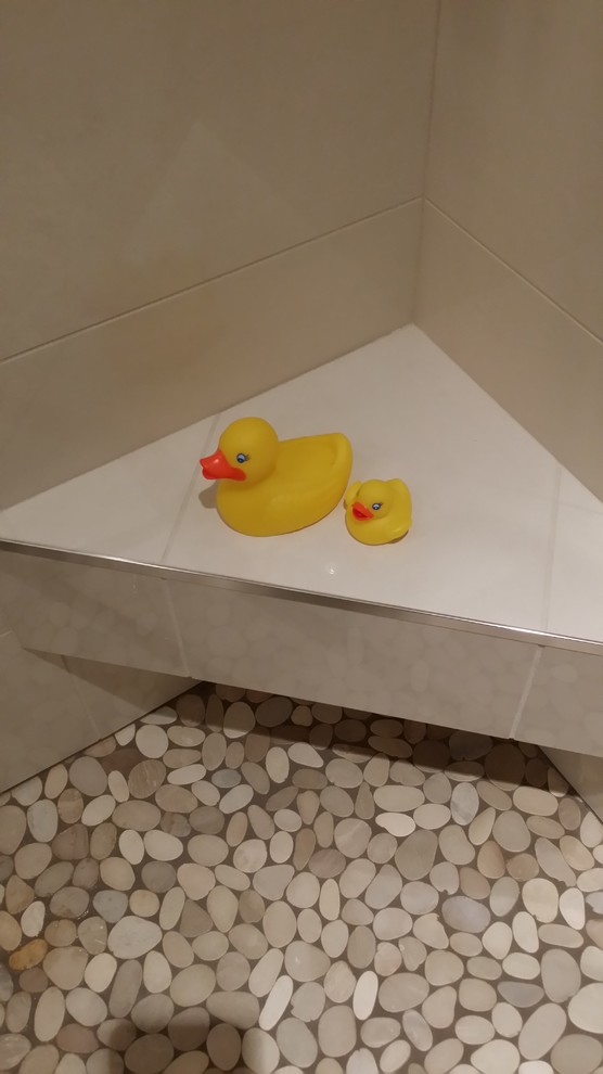 Cette photo montre une salle de bain tendance avec un lavabo de ferme, une douche d'angle, WC séparés, un carrelage gris, des carreaux de porcelaine, un mur beige et un sol en galet.