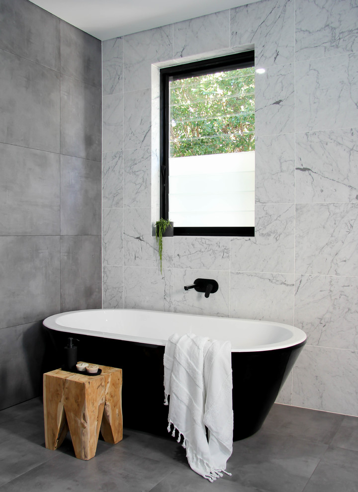 Idée de décoration pour une salle de bain principale design avec une baignoire indépendante, un carrelage gris, un carrelage blanc, du carrelage en marbre, un mur blanc, sol en béton ciré et un sol gris.