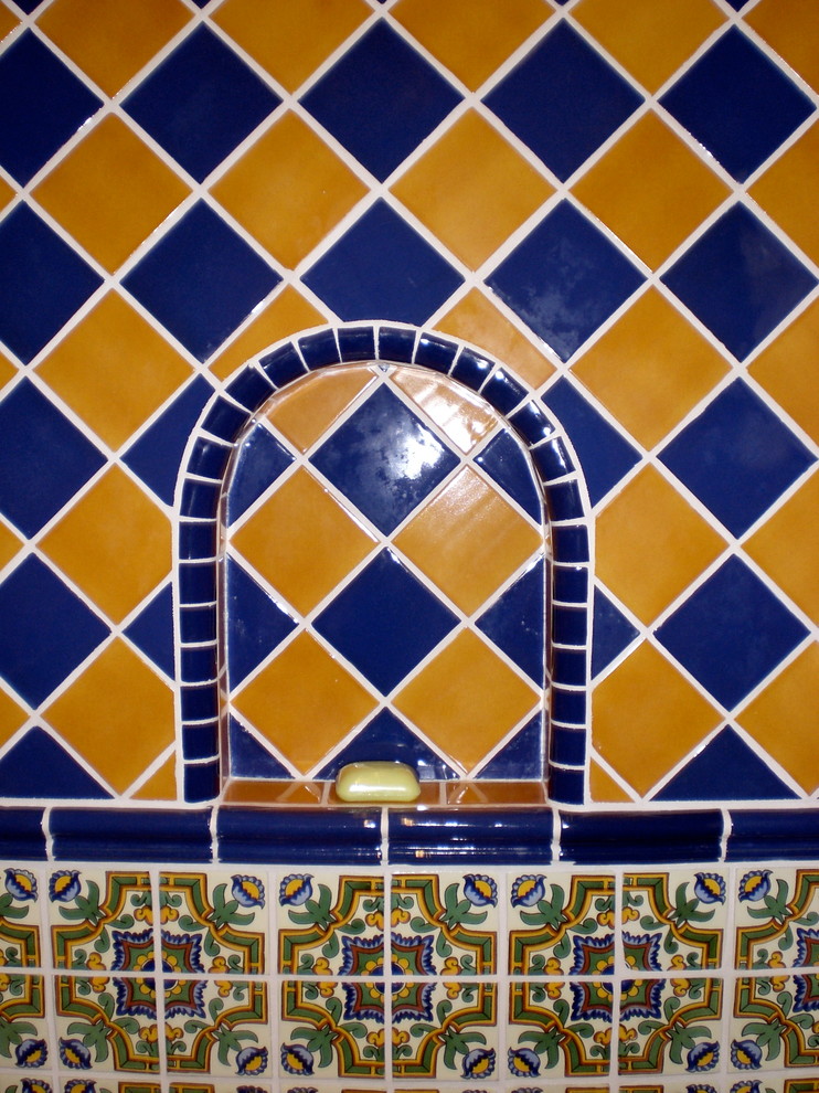 Modelo de cuarto de baño principal mediterráneo de tamaño medio con armarios con paneles con relieve, puertas de armario de madera oscura, encimera de azulejos, baldosas y/o azulejos de cerámica, ducha abierta, sanitario de una pieza, lavabo encastrado, paredes blancas, bañera esquinera, baldosas y/o azulejos azules, baldosas y/o azulejos amarillos y suelo de baldosas de terracota