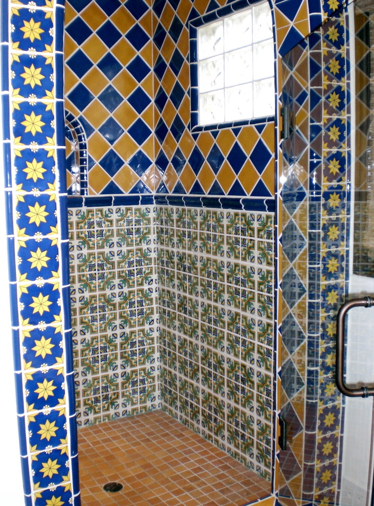 Design ideas for a medium sized mediterranean ensuite bathroom with raised-panel cabinets, medium wood cabinets, tiled worktops, blue tiles, yellow tiles, ceramic tiles, a walk-in shower, a one-piece toilet, a built-in sink, white walls, a corner bath and terracotta flooring.