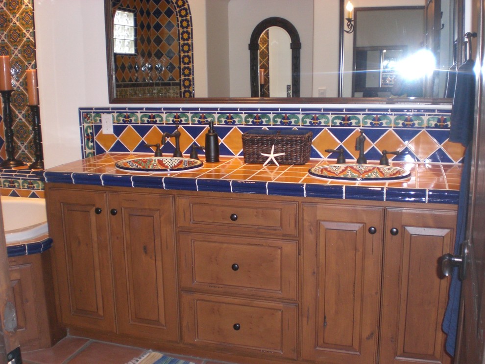 Стильный дизайн: главная ванная комната среднего размера в средиземноморском стиле с фасадами с выступающей филенкой, фасадами цвета дерева среднего тона, столешницей из плитки, синей плиткой, желтой плиткой, керамической плиткой, угловой ванной, открытым душем, унитазом-моноблоком, накладной раковиной, белыми стенами и полом из терракотовой плитки - последний тренд