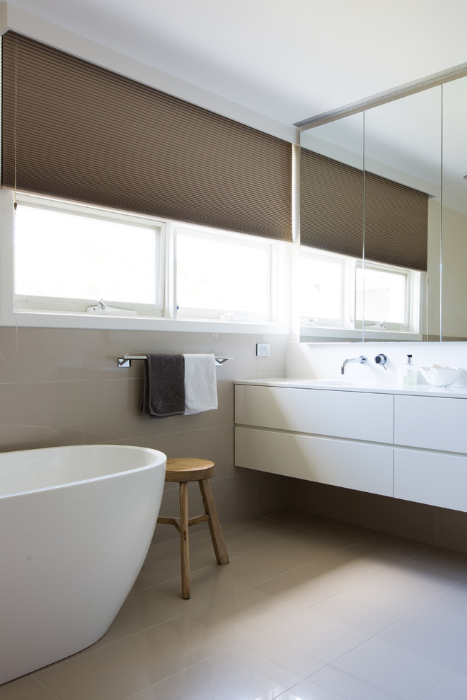 メルボルンにあるコンテンポラリースタイルのおしゃれなマスターバスルーム (フラットパネル扉のキャビネット、白いキャビネット、置き型浴槽、ベージュの壁) の写真