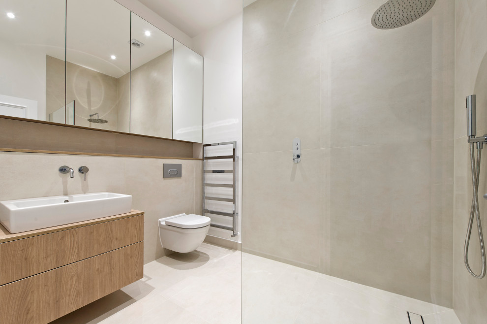 Medium sized contemporary bathroom in London with flat-panel cabinets, light wood cabinets, a wall mounted toilet, beige tiles, ceramic tiles, beige walls, ceramic flooring, a console sink, wooden worktops and beige floors.