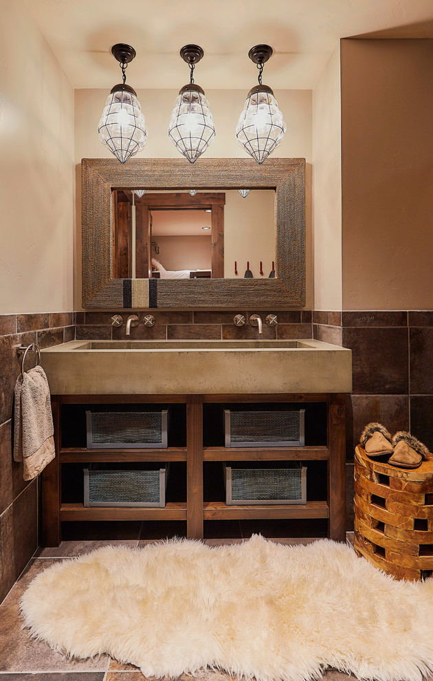 Rustik inredning av ett en-suite badrum, med öppna hyllor, skåp i mörkt trä, brun kakel, beige väggar och ett avlångt handfat