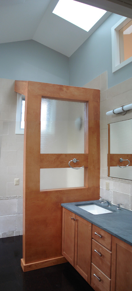 Example of a mid-sized minimalist master beige tile and limestone tile cork floor and brown floor bathroom design in New York with shaker cabinets, medium tone wood cabinets, a one-piece toilet, an undermount sink and a hinged shower door