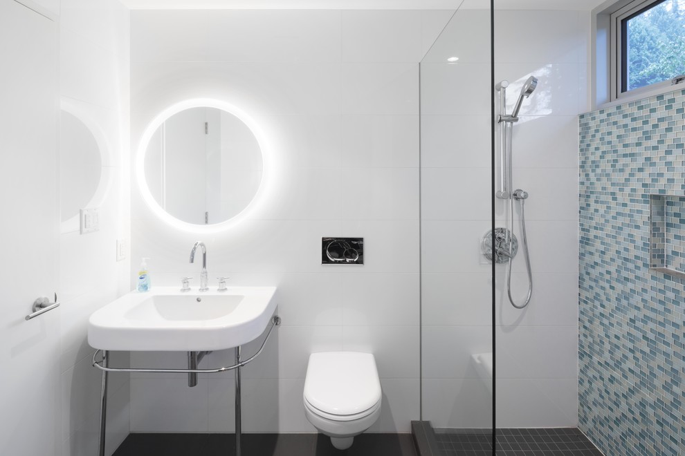Modelo de cuarto de baño actual con ducha empotrada, sanitario de pared, baldosas y/o azulejos azules, baldosas y/o azulejos en mosaico, aseo y ducha, lavabo tipo consola y suelo negro