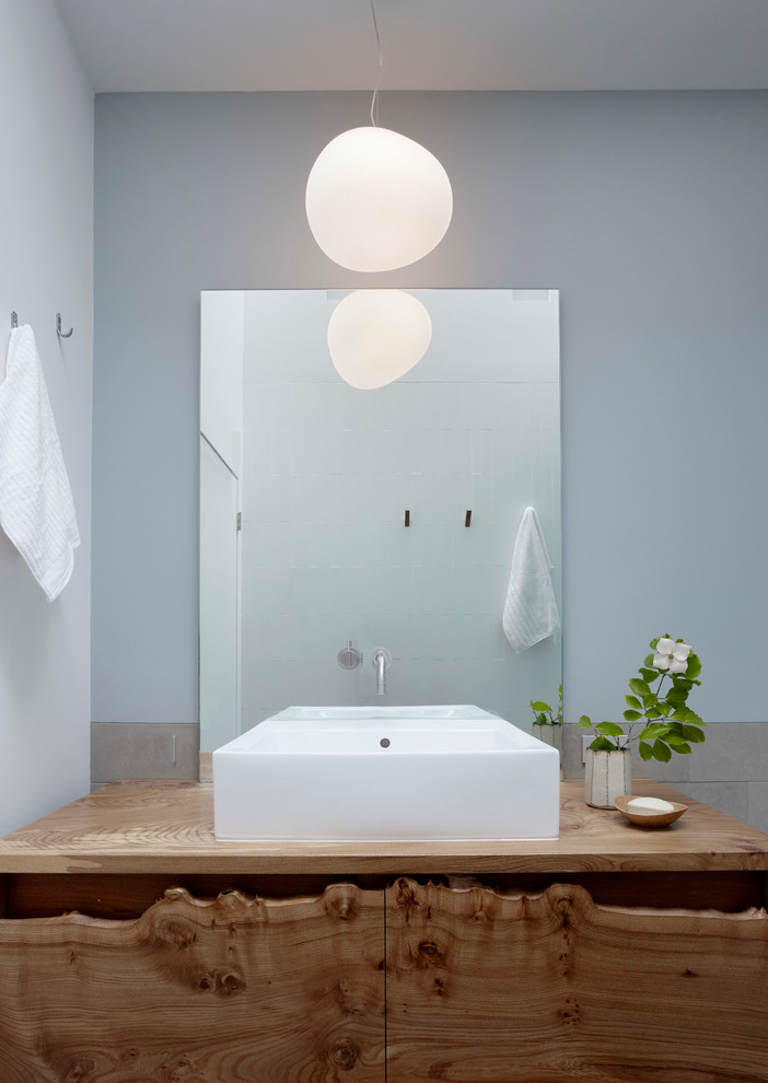 На фото: ванная комната в современном стиле с настольной раковиной и столешницей из дерева с