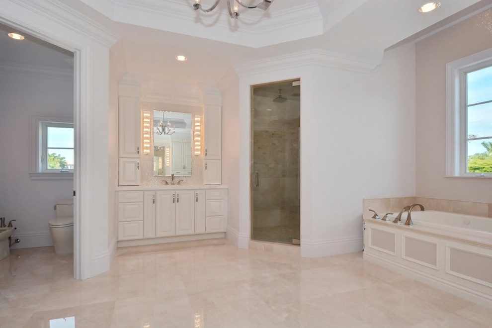 Example of a large transitional master mosaic tile and beige tile marble floor and beige floor bathroom design in Miami with an undermount sink, raised-panel cabinets, white cabinets, marble countertops, white walls, a two-piece toilet and a hinged shower door