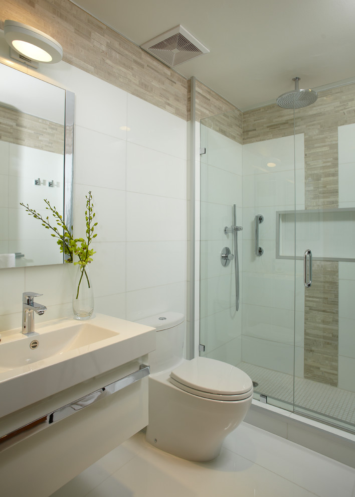 Inredning av ett modernt mellanstort badrum, med ett konsol handfat, släta luckor, vita skåp, marmorbänkskiva, ett platsbyggt badkar, en kantlös dusch, en toalettstol med hel cisternkåpa, vit kakel, mosaik, vita väggar och marmorgolv