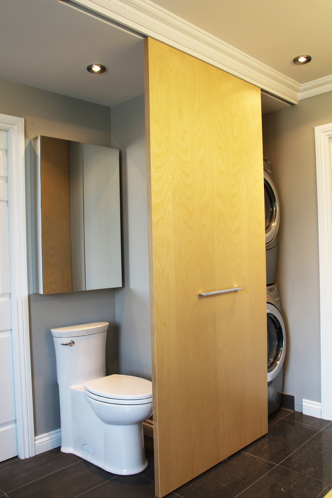 Exemple d'une grande salle de bain principale tendance avec un placard à porte plane, des portes de placard grises, une baignoire indépendante, une douche d'angle, WC à poser, un carrelage gris, des carreaux de porcelaine, un mur gris, un sol en carrelage de porcelaine, une vasque et un plan de toilette en bois.