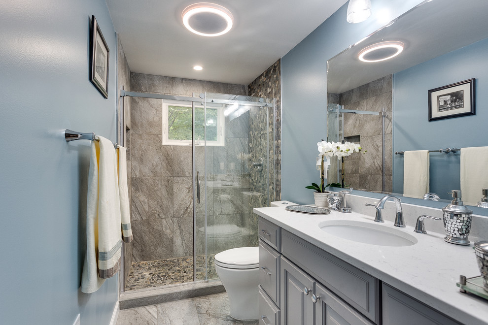 Klassisk inredning av ett mellanstort en-suite badrum, med luckor med upphöjd panel, grå skåp, en dusch i en alkov, en toalettstol med separat cisternkåpa, grå kakel, stenkakel, blå väggar, klinkergolv i keramik, ett undermonterad handfat och laminatbänkskiva