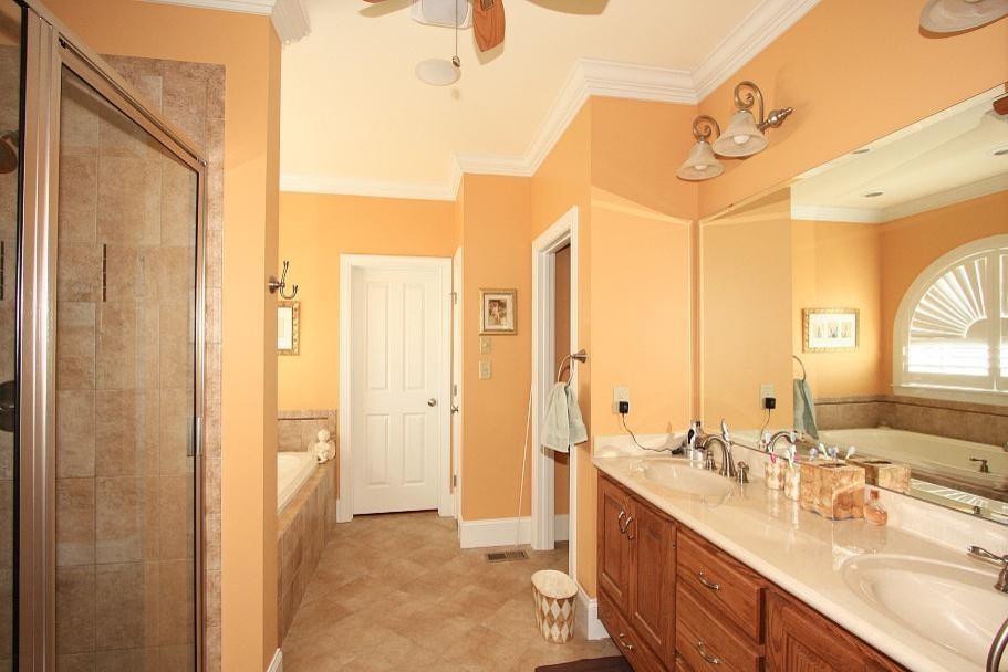 Example of a mid-sized classic master beige tile bathroom design in Raleigh with raised-panel cabinets, medium tone wood cabinets and yellow walls