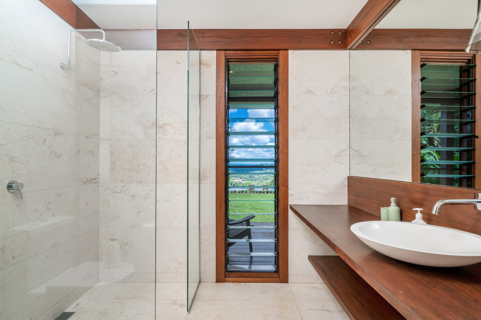 Inspiration för ett tropiskt brun brunt badrum med dusch, med en kantlös dusch, beige kakel, beige väggar, ett fristående handfat, träbänkskiva, beiget golv och med dusch som är öppen
