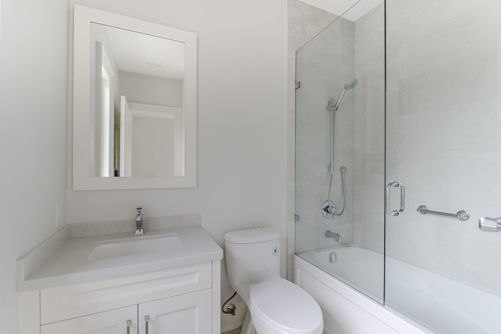 This is an example of a small contemporary family bathroom in Toronto with shaker cabinets, white cabinets, a corner bath, a shower/bath combination, a one-piece toilet, a submerged sink, granite worktops and a hinged door.