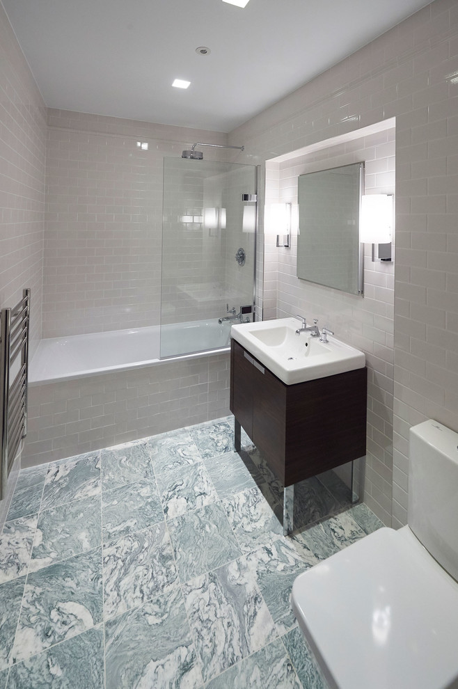 Medium sized contemporary ensuite bathroom in London with a built-in bath, a shower/bath combination, porcelain flooring, freestanding cabinets, dark wood cabinets, white tiles, white walls and a console sink.
