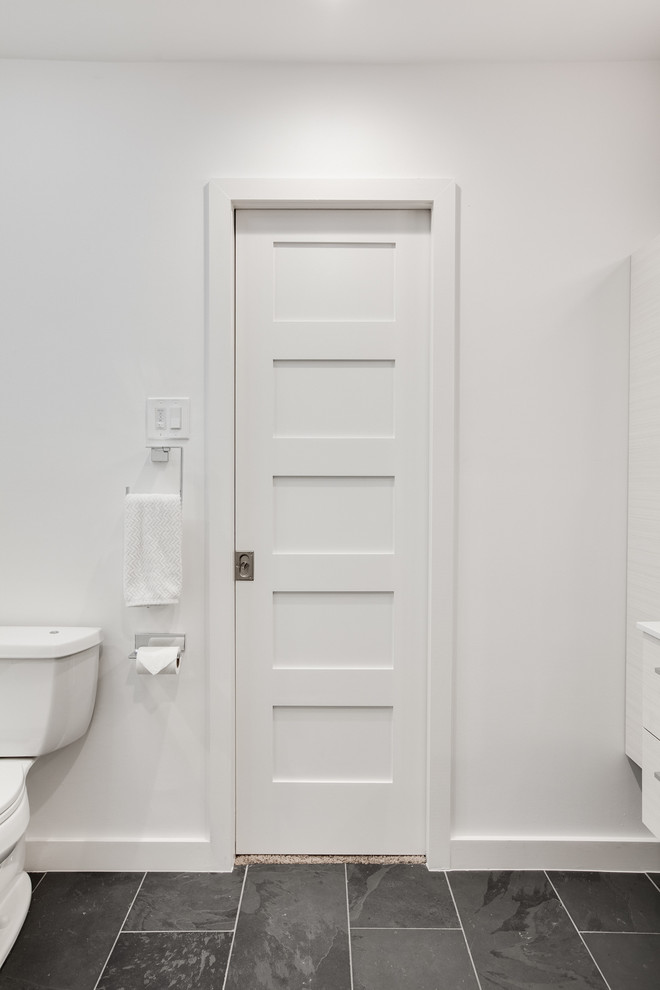 Exemple d'une grande salle de bain principale tendance avec un placard à porte plane, des portes de placard grises, une baignoire en alcôve, un combiné douche/baignoire, WC séparés, un carrelage gris, mosaïque, un mur blanc, un sol en ardoise, un lavabo intégré et un plan de toilette en surface solide.