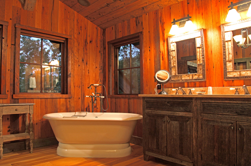 Foto de cuarto de baño rústico con armarios con paneles con relieve, puertas de armario de madera oscura, encimera de granito y bañera exenta