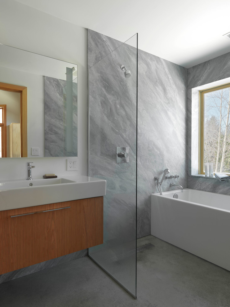 Modern inredning av ett stort en-suite badrum, med släta luckor, skåp i mellenmörkt trä, ett fristående badkar, våtrum, grå kakel, stenhäll, vita väggar, betonggolv, ett integrerad handfat, bänkskiva i akrylsten, grått golv och med dusch som är öppen