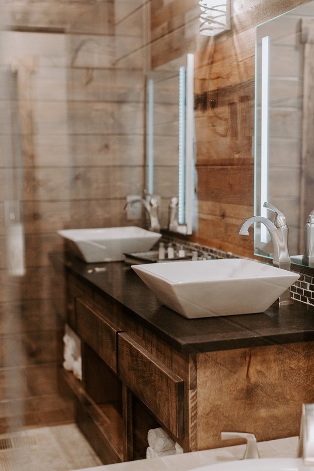На фото: большая главная ванная комната в стиле рустика с темными деревянными фасадами, накладной ванной, коричневой плиткой, коричневыми стенами, настольной раковиной, столешницей из искусственного кварца и черной столешницей с