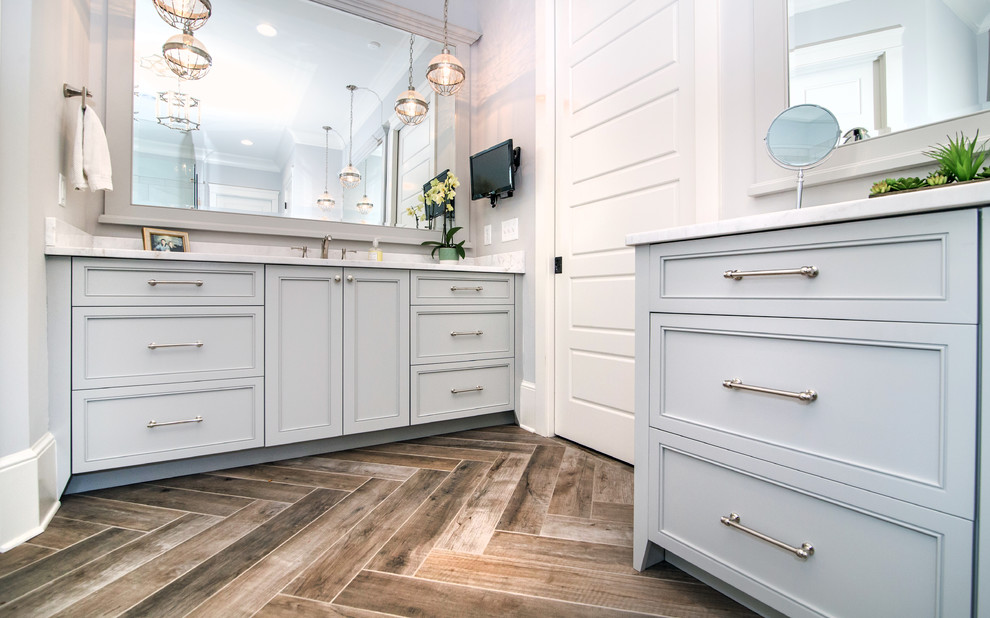 Klassisk inredning av ett stort vit vitt en-suite badrum, med släta luckor, grå skåp, vita väggar, klinkergolv i porslin, ett undermonterad handfat, bänkskiva i kvarts och brunt golv
