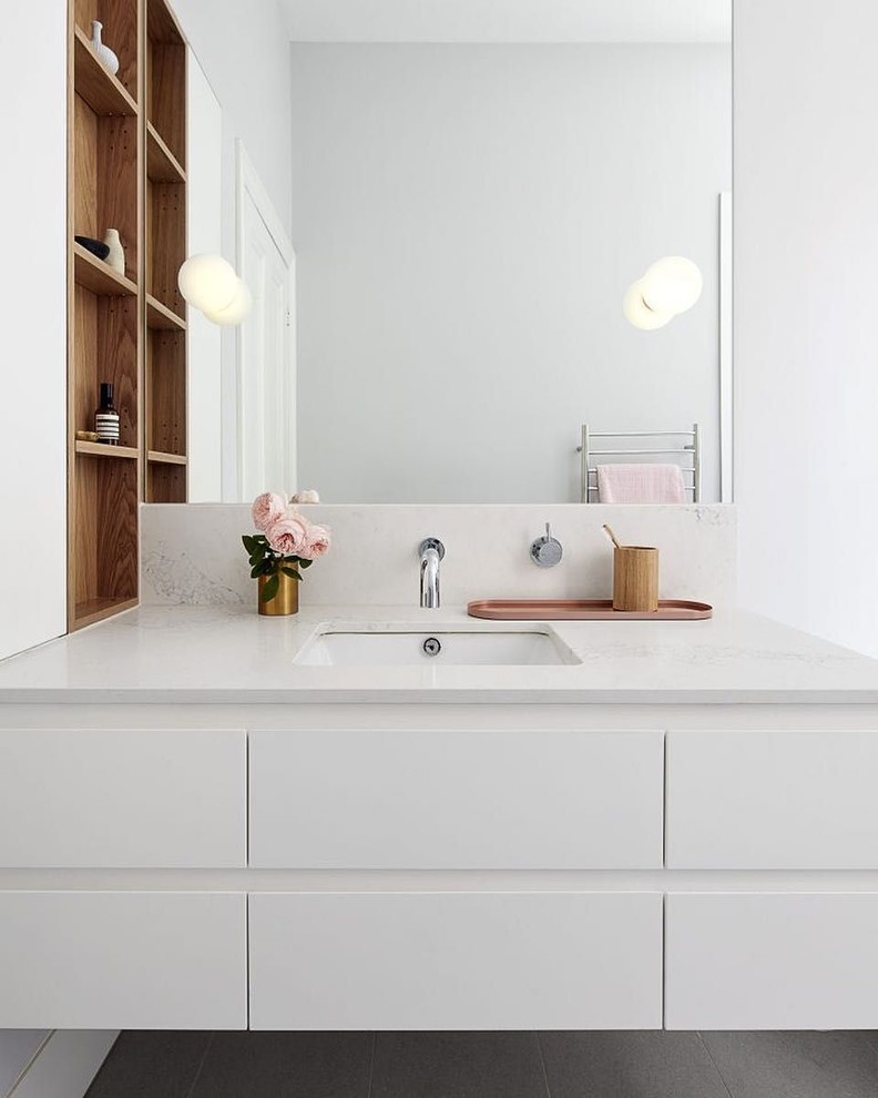 На фото: ванная комната в современном стиле с плоскими фасадами, белыми фасадами, белыми стенами, полом из ламината, врезной раковиной, столешницей из кварцита, серым полом и белой столешницей
