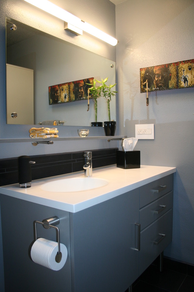 Immagine di una piccola stanza da bagno con doccia minimal con lavabo integrato, ante lisce, ante grigie, top in superficie solida, piastrelle nere, piastrelle in ceramica e pareti grigie