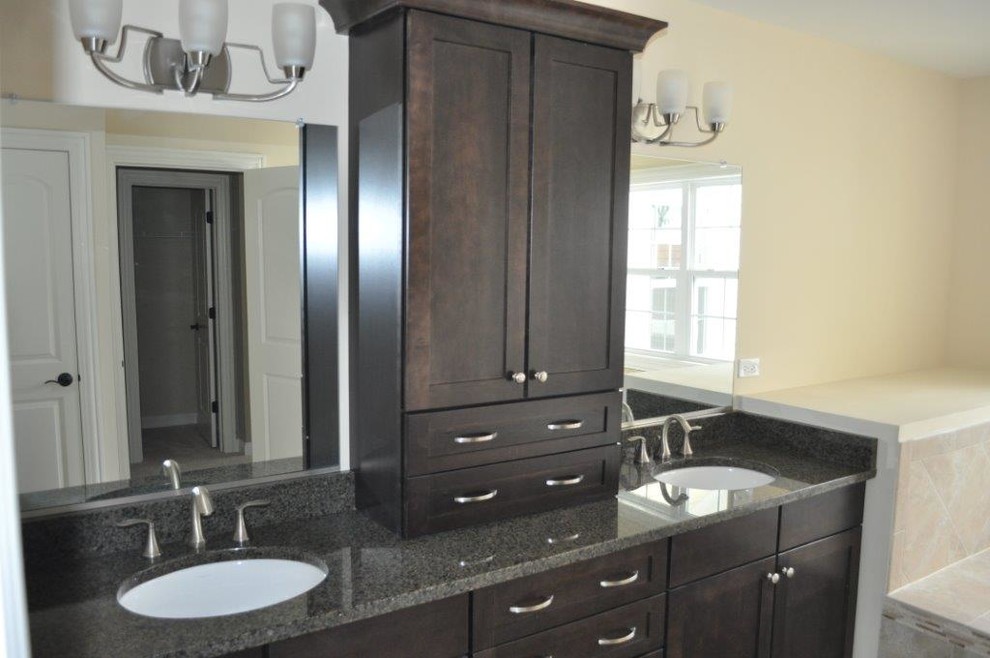 Cette photo montre une salle de bain principale tendance en bois foncé de taille moyenne avec un placard à porte shaker, un mur beige, un lavabo encastré et un plan de toilette en granite.